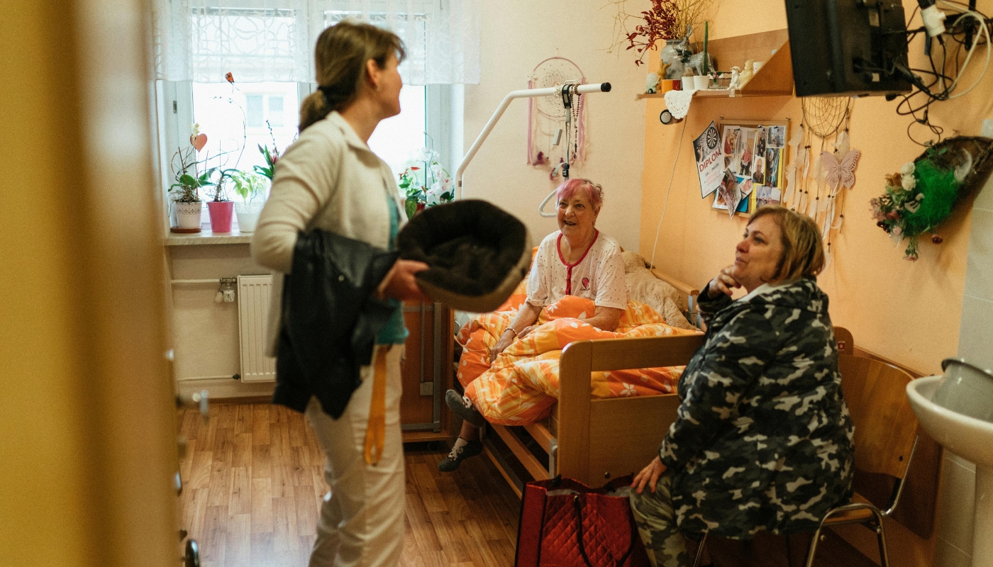 ممرضة تقدم الرعاية لرجل مسن داخل دار رعاية مميزة في كورنيش النيل بالقاهرة، مع إطلالة طبيعية على نهر النيل