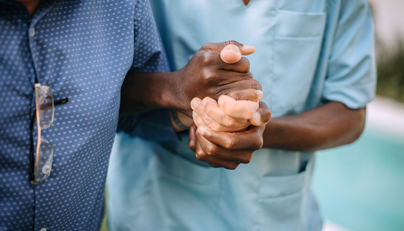 ممرضة تساعد أحد كبار السن بابتسامة دافئة داخل دار مسنين في حدائق حلوان، تعبير عن إنسانية الرعاية ودفء الاهتمام