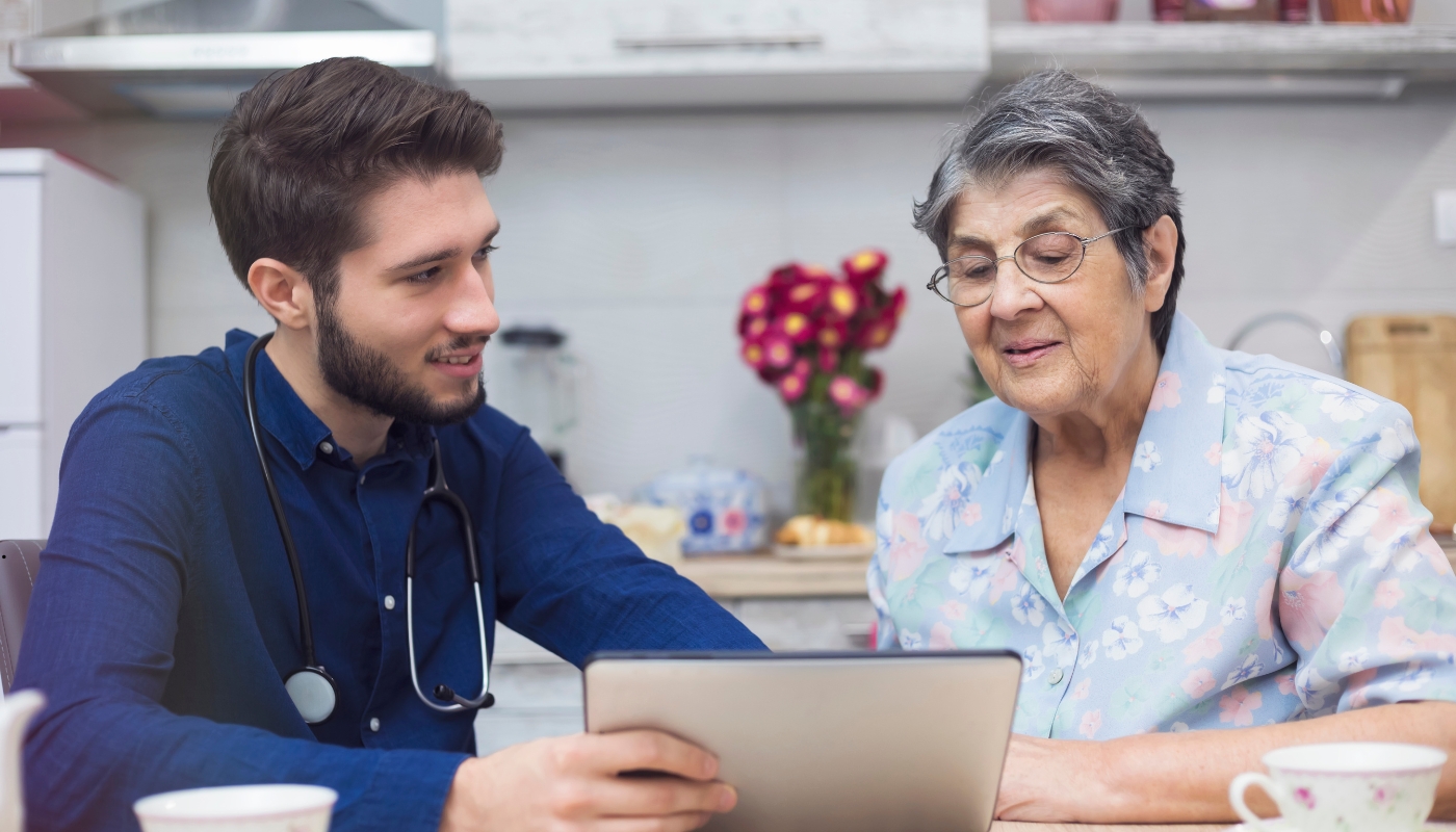 ممرضة تقدم الرعاية والحنان لرجل مسن في دار رعاية كبار السن، تعبيرًا عن الإنسانية والمسؤولية الاجتماعية