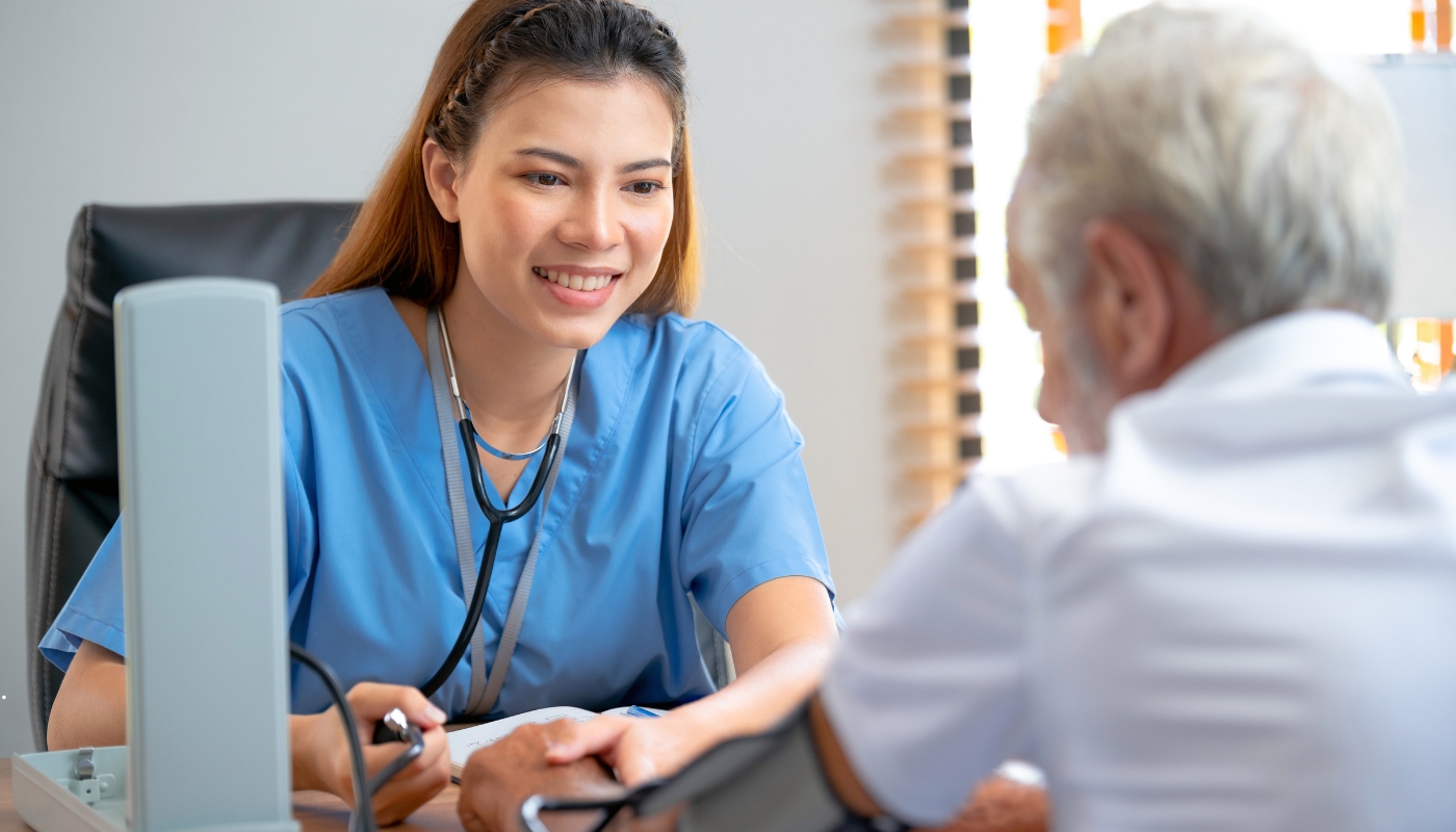 ممرضة تساعد أحد كبار السن بابتسامة في دار رعاية، تجسّد مفهوم الرعاية المتكاملة التي تجمع بين الدعم الطبي والنفسي