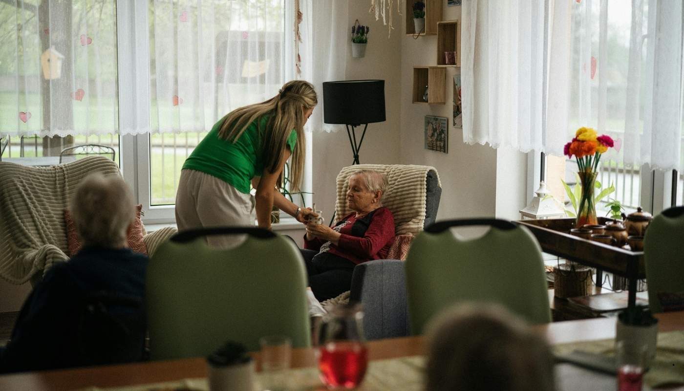 ممرضة تساعد مسن في التمارين اليومية داخل دار رعاية.