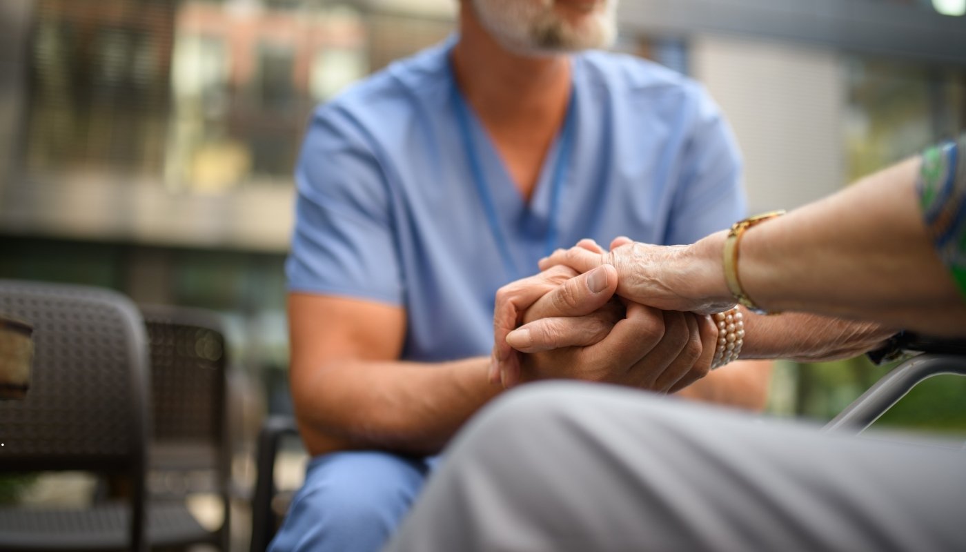 ممرضة تقوم بقياس مستوى السكر لمسن داخل دار مسنين، مع الاهتمام الطبي والإنساني لضمان الرعاية الاحترافية