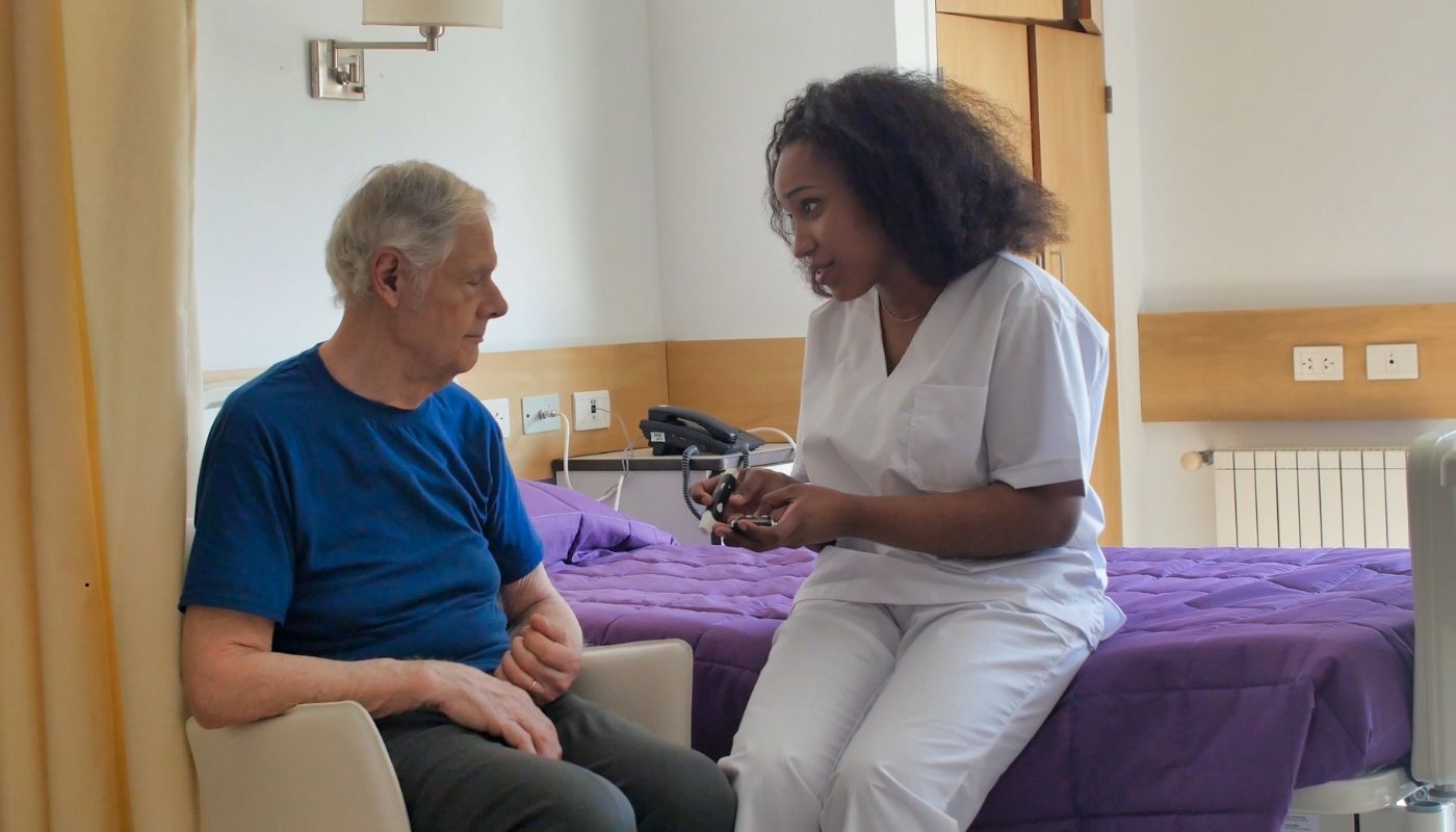 ممرضة تقدم الرعاية والدعم لكبير سن داخل دار مسنين، تعكس أهمية رعاية كبار السن والاهتمام بصحتهم وراحتهم